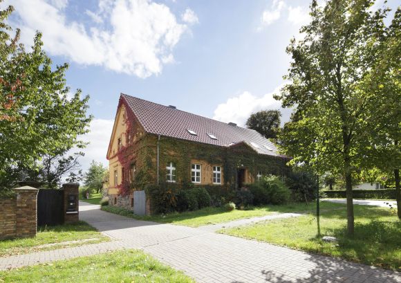 Unser Gebäude am Standort in Rohlack, efeuüberwuchertes Haus mit Einfahrt in sommerlicher Stimmung