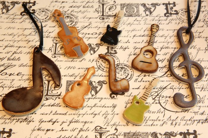 Kunstvolle Anhänger: Noten und Musikinstrumente aus Keramik liegen auf altem Papier