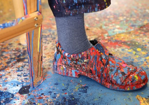 Ein mit verschiedenen Farben besprenkelter Schuh eines Künstlers in unserer Kunstwerkstatt