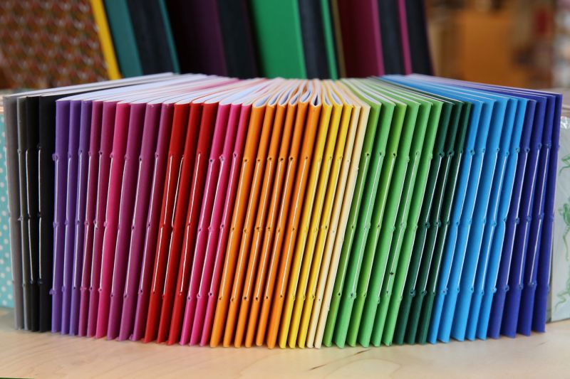 Heftrücken von Heften in Regenbogenfarben von schwarz violett rot orange gelb grün bis blau