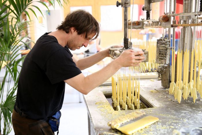 Mitarbeiter unserer Kerzenmanufaktur an der Kerzenmaschine mit gelben Kerzen