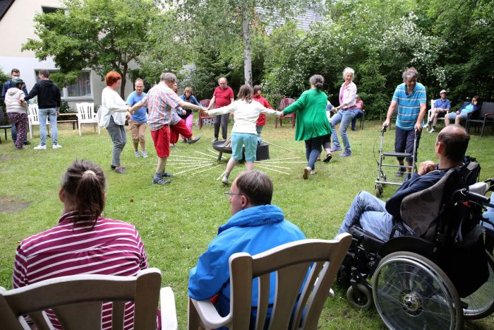 Bewohner der LebensOrte tanzen im Kreis beim Sommerfest