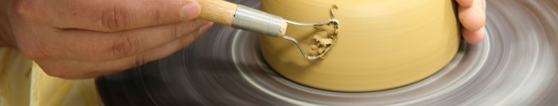 Hände einer Keramikerin an der Drehscheibe in Bewegung, eine Schale wird in unserer Keramikwerkstatt fertig erstellt